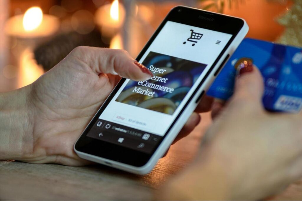 スマートフォンでECサイトを表示し、片手にクレジットカードを持って決済準備をする人の手元。