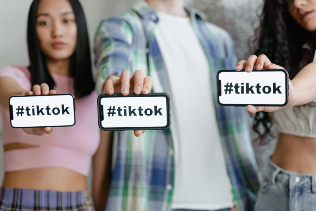 TikTok Shopを象徴するハッシュタグを表示したスマートフォンを若者たちが手に持っている様子